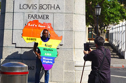 A passerby is photographed with his head inside a rainbow Africa cutout, underneath the statue of Louis Botha at Parliament. (Photo: Naib Mian)
